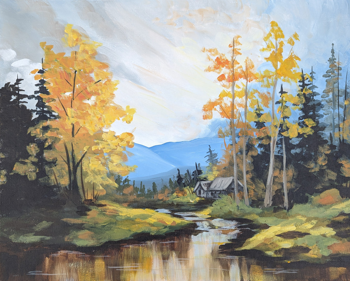 A framed art print of an autumn landscape with vibrant golden-yellow trees by a river with distant mountains in the background under a cloudy sky