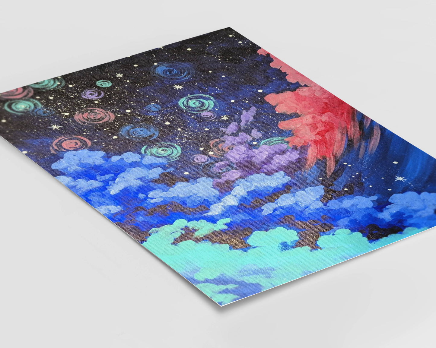 A framed art print showing a night sky with swirling clouds in shades of pink and blue filled with glowing stars and spirals