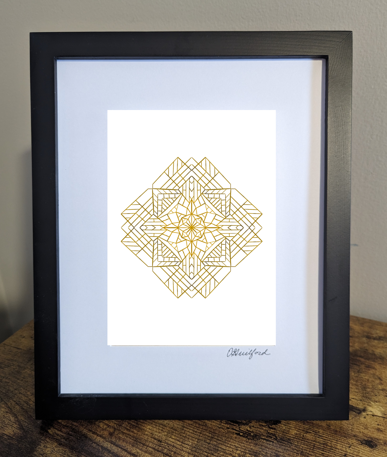 Art work featuring a detailed geometric mandala design in gold lines intricately layered to form a symmetrical pattern