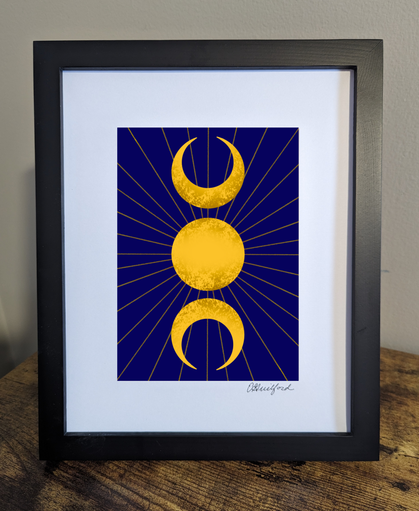 A celestial art print featuring the triple moon symbol, with two crescent moons flanking a full sun all in gold