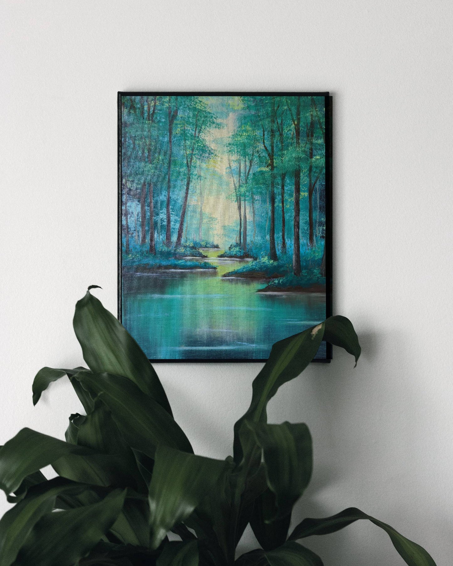 A tranquil framed art print depicting tall trees alongside a calm river illuminated by soft sunlight filtering through the trees