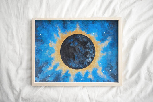 A framed eclipse art print depicting the sun’s corona glowing brightly against a dark sky