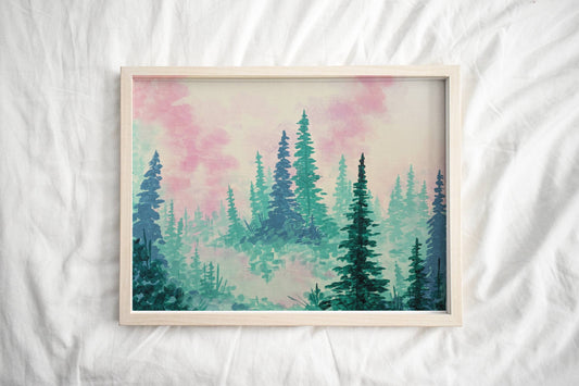 A framed forest art print of tall pine trees fading into the mist set against a pastel pink and blue sky