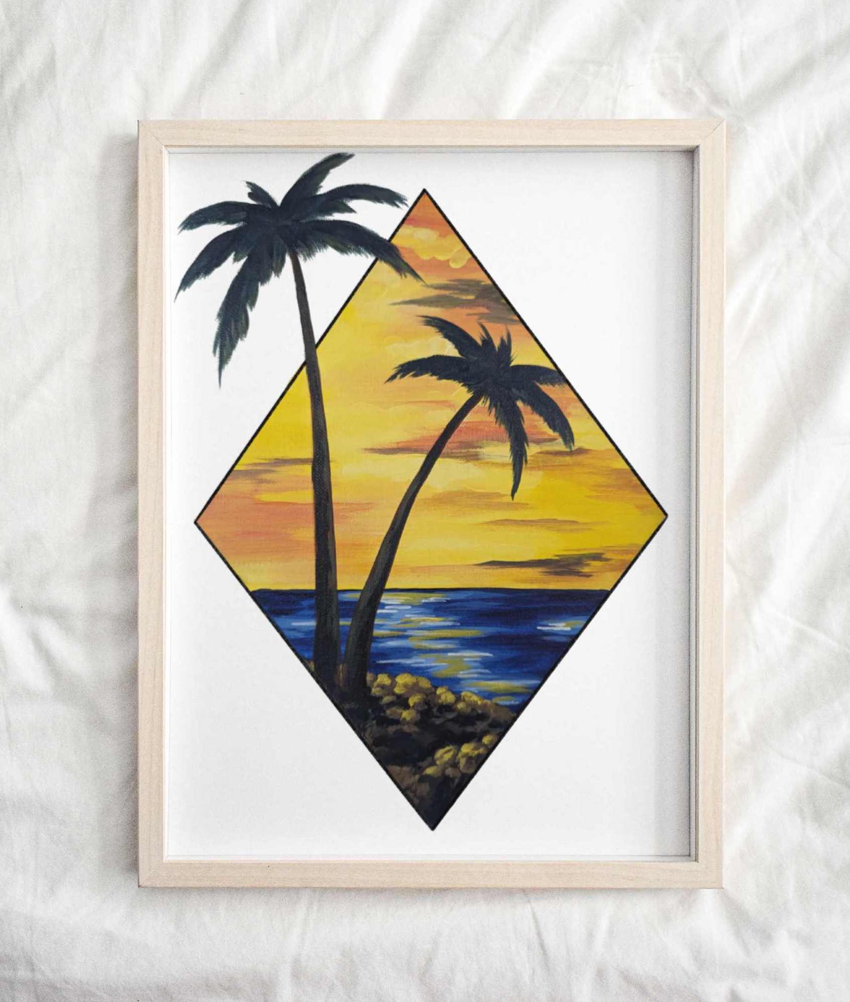 Framed art print featuring a scenic view of two palm trees by the water at sunset