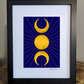 A celestial art print featuring the triple moon symbol, with two crescent moons flanking a full sun all in gold